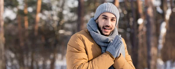 Позитивний чоловік у теплому одязі, дивлячись на камеру в зимовому парку, банер — стокове фото