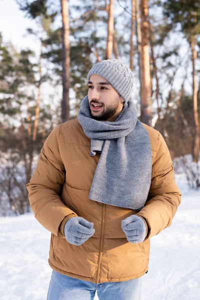 Uomo sorridente in abiti caldi guardando lontano nel parco — Foto stock