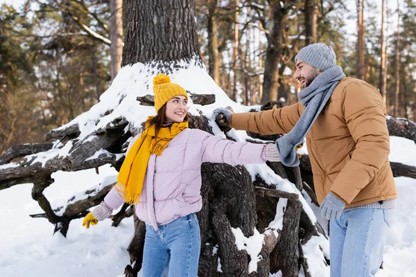 Jeune couple s'amusant près de l'arbre avec de la neige dans le parc — Photo de stock