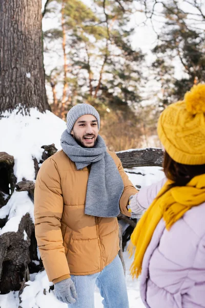 Sonriente hombre cogido de la mano de novia borrosa en el parque de invierno - foto de stock