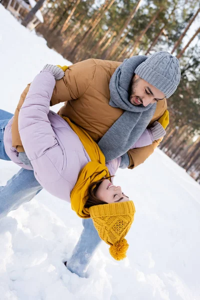 Молодий чоловік розважається з дівчиною в зимовому вбранні на відкритому повітрі — стокове фото