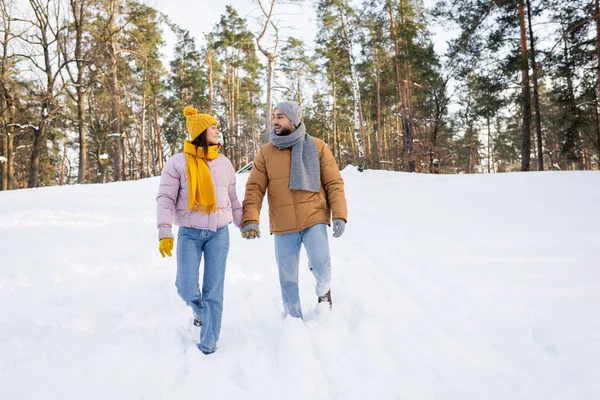 Jeune couple tenant la main tout en marchant sur la neige — Photo de stock