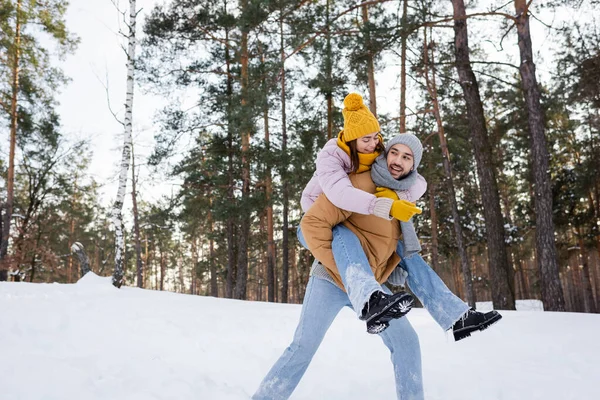 Glückliche Frau huckepack auf Freund, während sie Spaß im Winterpark hat — Stockfoto