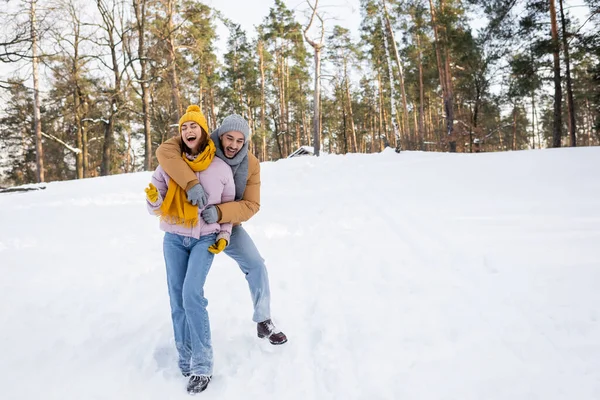 Счастливый мужчина обнимает смеющуюся девушку в зимнем парке — стоковое фото