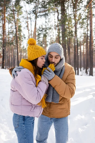 Young couple warming hands in gloves in winter park — Stock Photo
