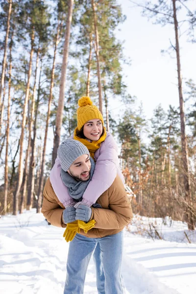 Donna allegra che abbraccia il fidanzato e distoglie lo sguardo nel parco invernale — Foto stock