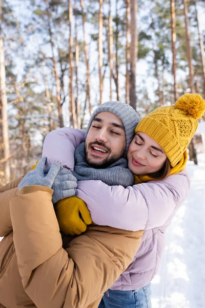 Junge Frau umarmt Freund mit geschlossenen Augen im Winterpark — Stockfoto