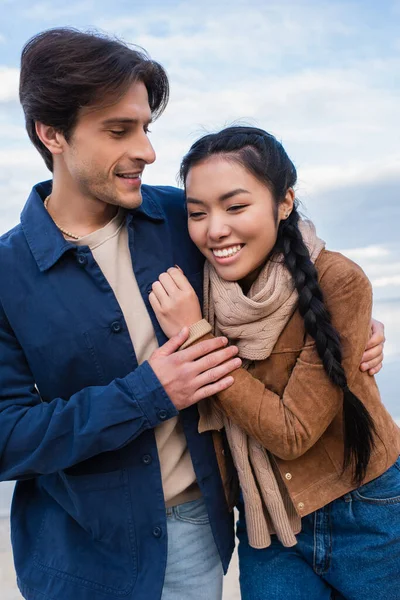 Positive multiethnic couple hugging outdoors during weekend — Stock Photo