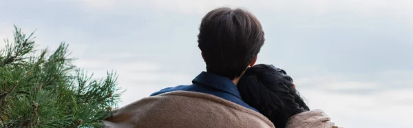 Back view of couple in blanket standing near fir branch outdoors, banner — Stock Photo