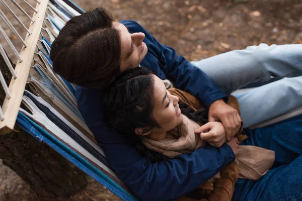 Visão aérea de feliz casal interracial abraçando na rede ao ar livre — Fotografia de Stock