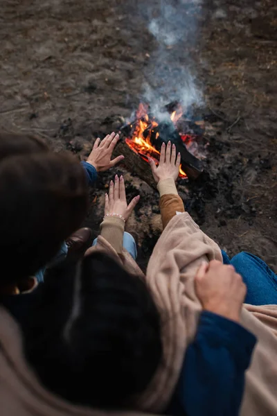 Overhead view of couple warming hands near campfire — Stock Photo
