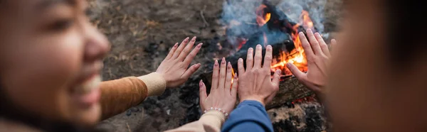 Blurred couple warming hands near campfire, banner — Stock Photo