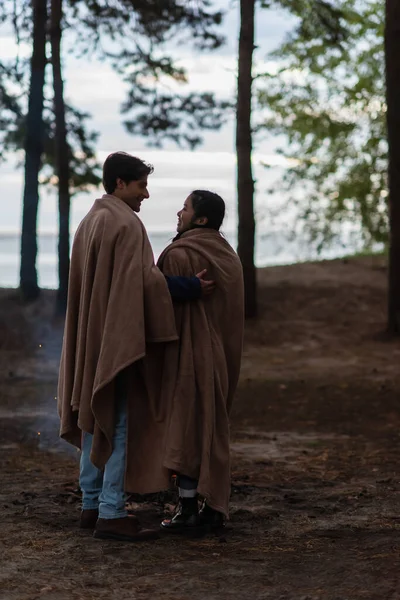 Side view of interracial couple in blankets standing outdoors during weekend — Stock Photo