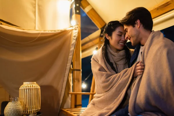 Asian woman hugging boyfriend in blanket on terrace of glamping house — Stock Photo