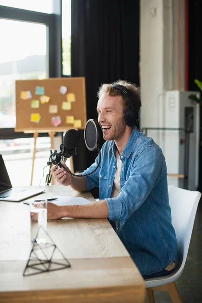 Позитивний радіоведучий в навушниках сміється в студії — стокове фото