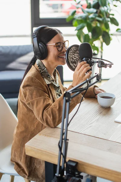 Gai asiatique radio hôte dans lunettes et écouteurs parler pendant podcast — Photo de stock