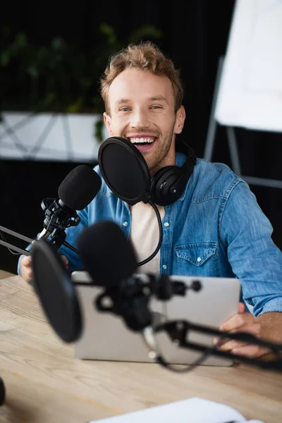 Positive radio host in headphones smiling in podcast studio — Stock Photo