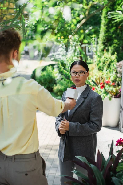 Journalist holding microphone and taking interview of asian woman in glasses — Stock Photo