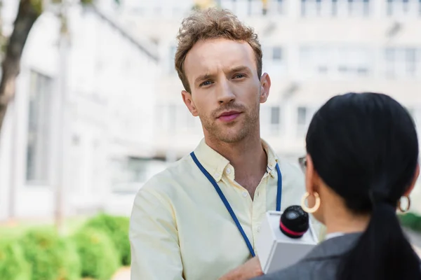 Reporter holding microphone near businesswoman and looking at camera — Stock Photo