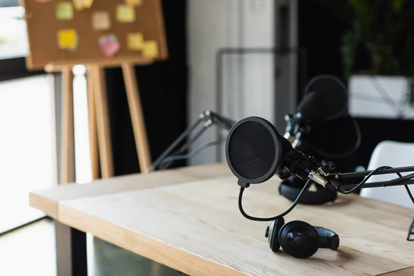 Filtre pop près du bras de ciseau réglable avec microphone et écouteurs sans fil sur le bureau — Photo de stock