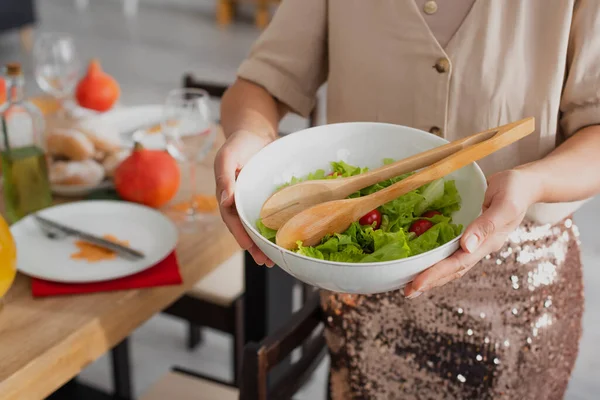 Cropped view of blurred african american woman holding salad near thanksgiving dinner — Stock Photo