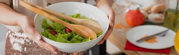 Vista cortada da mulher americana africana segurando salada fresca perto do jantar borrado em casa, banner — Fotografia de Stock