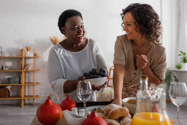 Madre afroamericana e hija adulta sirviendo juntos la cena de acción de gracias - foto de stock