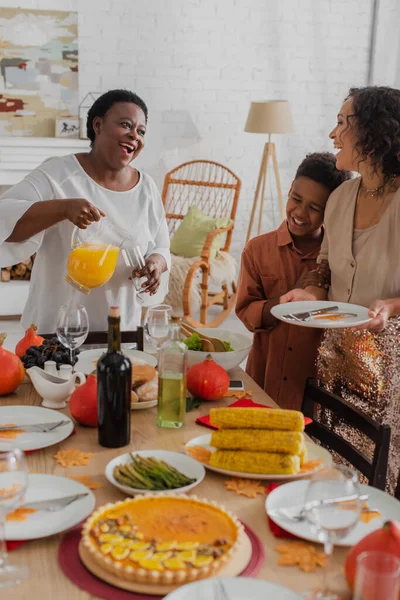 Улыбающаяся африканская американская семья с ребенком, подающим ужин в честь Дня благодарения — стоковое фото