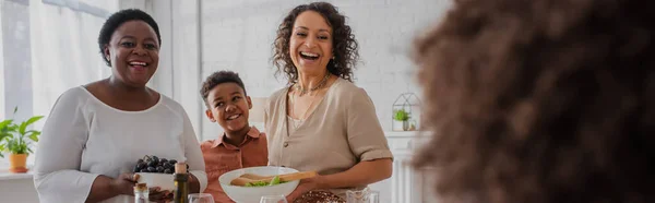 Cheerful african american family with food looking at blurred girl during thanksgiving celebration, banner — Stock Photo