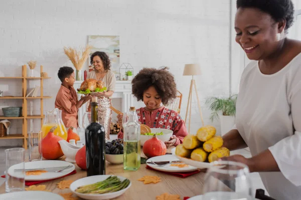 African american girl standing near served thanksgiving dinner and family at home — Stock Photo