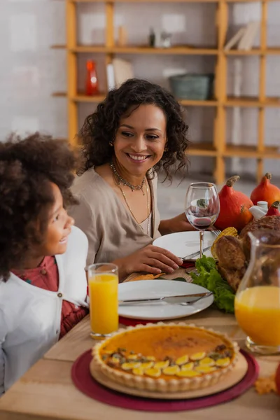 Lächelnde afrikanisch-amerikanische Mutter schaut Tochter beim Dankeschön-Dinner an — Stockfoto