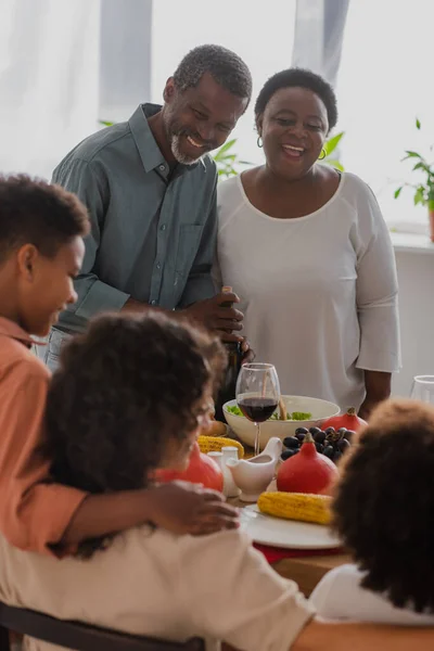 Avós afro-americanos alegres olhando para a família durante o jantar de ação de graças — Fotografia de Stock