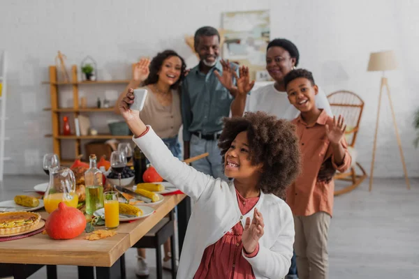 African american kid taking selfie near blurred family and thanksgiving dinner — Stock Photo
