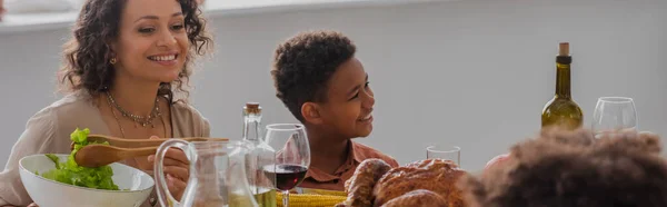 Madre e hijo afroamericanos sentados cerca de la cena de acción de gracias, pancarta - foto de stock