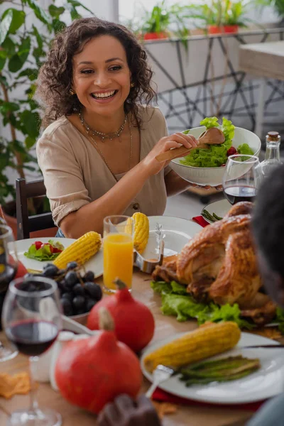 Glückliche afrikanisch-amerikanische Mutter hält Salat neben verschwommenem Vater und traditionellem Dankeschön-Dinner — Stockfoto