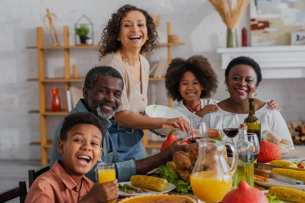 Sonriente familia afroamericana mirando a la cámara cerca de la cena de Acción de Gracias - foto de stock