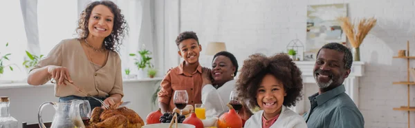 Sonriente familia afroamericana cerca de la cena de Acción de Gracias en casa, pancarta - foto de stock