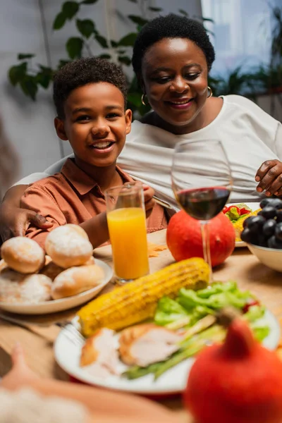 Joyeux garçon afro-américain souriant près de mamie heureuse pendant le dîner de Thanksgiving — Photo de stock