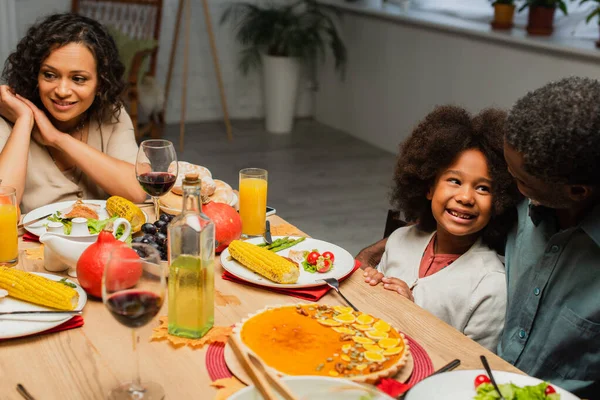 Africano americano ragazza sorridente vicino nonno e madre durante il Ringraziamento cena — Foto stock