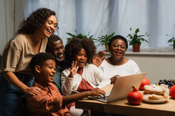 Felice famiglia afro-americana che agita le mani durante la videochiamata durante la cena del Ringraziamento — Foto stock