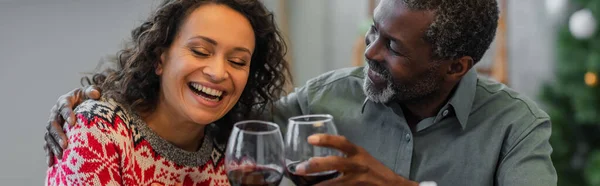 Allegro padre afroamericano e figlia bicchieri di vino rosso durante la celebrazione di Natale, striscione — Foto stock