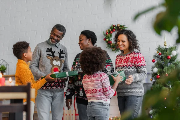 Niños afroamericanos presentando regalos de Navidad a la madre feliz y abuelos — Stock Photo