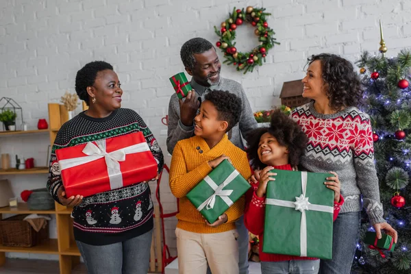 Compiaciuta famiglia afro-americana con regali di Natale che si guardano a casa — Foto stock