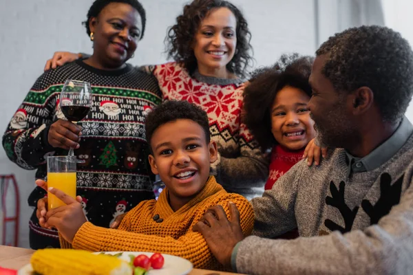 Glücklicher afrikanisch-amerikanischer Junge mit Orangensaft im Familienkreis beim Weihnachtsessen — Stockfoto