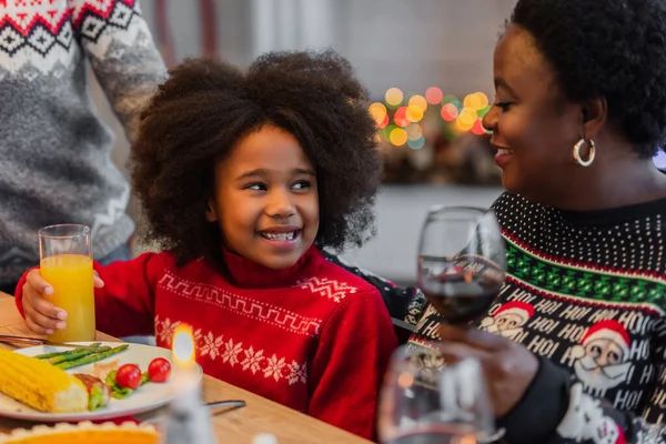 Афроамериканська дівчина посміхається біля щасливої бабусі під час різдвяної вечері — стокове фото