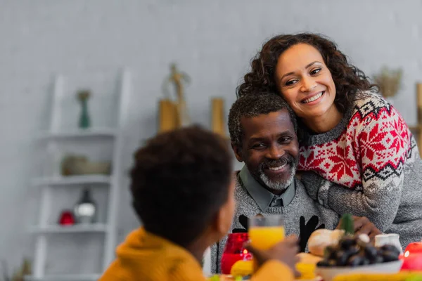 Joyeux père afro-américain et fille regardant le garçon flou pendant le dîner de Thanksgiving — Photo de stock