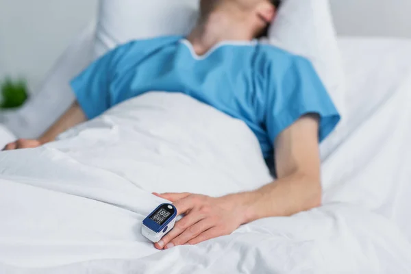 Teilaufnahme einer Patientin mit Oximeter am Finger, die im Krankenhausbett liegt — Stockfoto