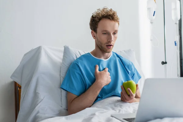 Malade ayant un appel vidéo tout en tenant pomme à l'hôpital — Photo de stock