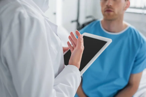 Cropped view of doctor in white coat holding digital tablet near patient — Stock Photo