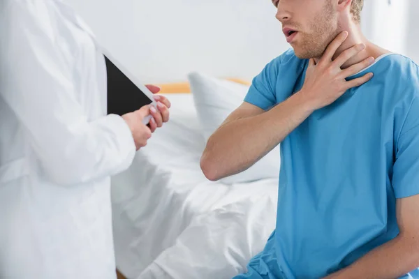 Cropped view of patient complaining on sore throat near doctor in white coat with digital tablet — Stock Photo